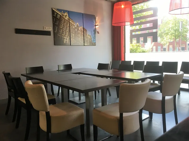 Table layout with tables pushed together and chairs around them, by the large window